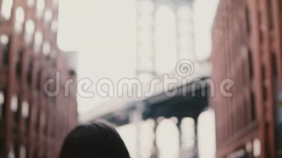从纽约Dumbo的角度拍摄布鲁克林大桥的照片带相机的快乐女游客走开了4K视频的预览图