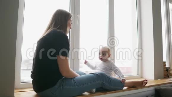妈妈带着孩子坐在窗前玩视频的预览图