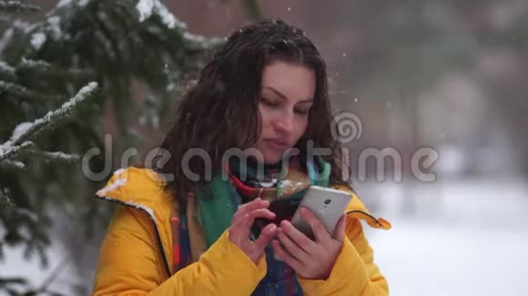 一个女孩带着智能手机的肖像当雪球击中她的脸时那个女人生气了冬季运动会视频的预览图