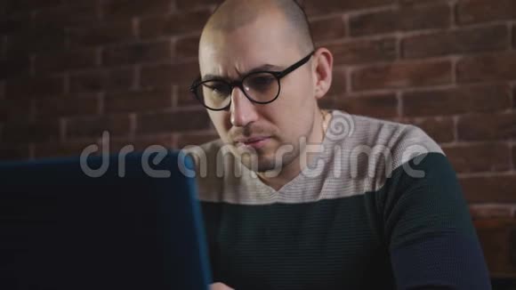 戴眼镜的人热衷于在笔记本电脑上工作一位男性作家正在笔记本电脑键盘上打字特写视频的预览图