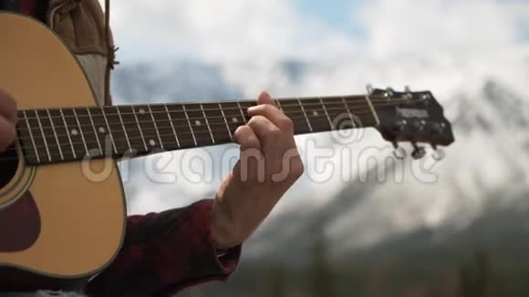 男游客手弹吉他的特写镜头雪山视频的预览图