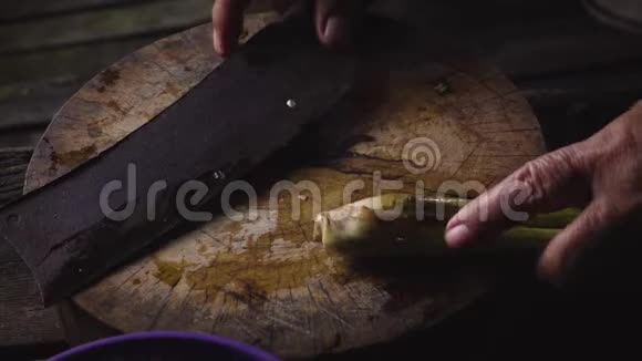 一位老太太的手在木切割板上切柠檬草视频的预览图