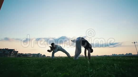 两个人在草地上练习夏天日落时视频的预览图