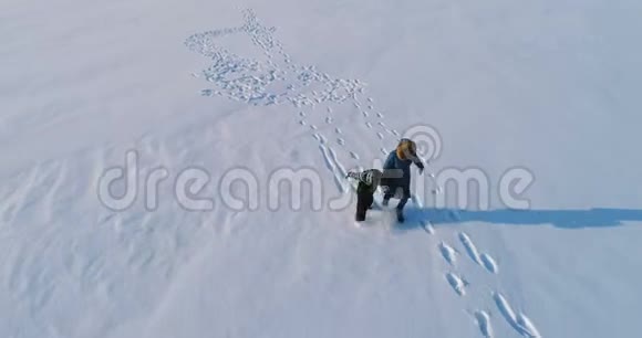 妈妈和太阳在雪地里一起跑步和玩耍空中镜头冬天的家庭消遣视频的预览图