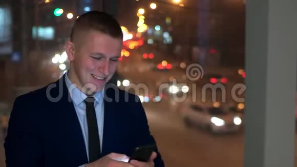 这位男商人看着智能手机高兴高兴窗外对着夜城视频的预览图