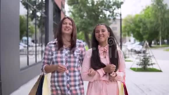 两个穿着连衣裙的年轻女孩购物后带着包裹购物心情很好4K视频的预览图