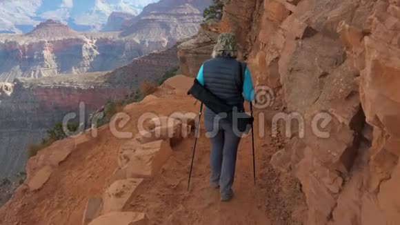 一条蜿蜒曲折的蛇形小径上的大峡谷上的女子徒步旅行视频的预览图