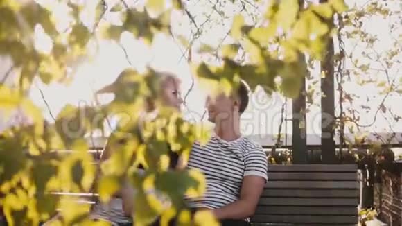 慢动作和平浪漫的情侣坐在秋日公园的长凳上谈论着计划和梦想视频的预览图