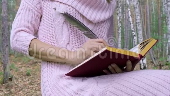 幸福迷人的微笑女人在春天的森林里用羽毛写诗视频的预览图