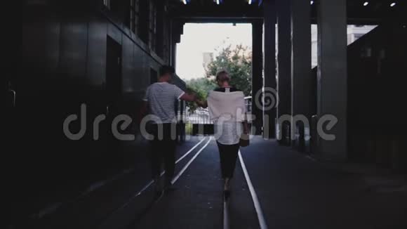 慢动作后景幸福浪漫的情侣一起散步双手在黑暗的黄昏城市桥下的铁轨上视频的预览图