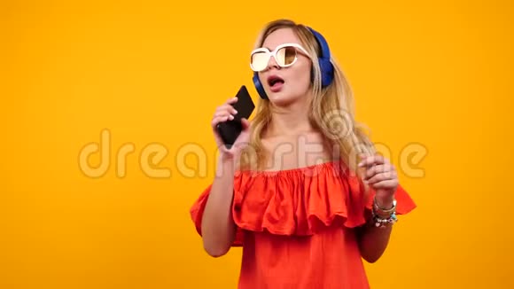 金发女人手里拿着智能手机唱歌跳舞视频的预览图