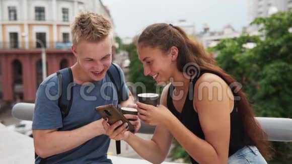 年轻的幸福夫妇看着智能手机屏幕笑着看着华尔街视频的预览图