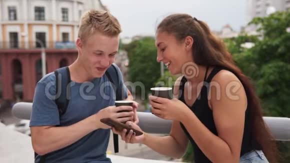 两个年轻快乐的人看着智能手机微笑着看着城市街道视频的预览图