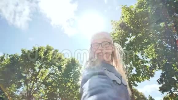美丽的12岁少女在阳光和树木的背景下用摄像机自拍视频的预览图