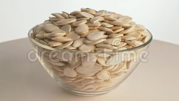坚果未剥皮南瓜种子旋转是在一个桌子在一个盘子在白色背景上的透明盘子中提供小吃视频的预览图