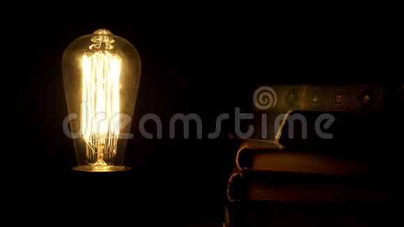 老式灯泡在复古书附近的黑暗中开关视频的预览图