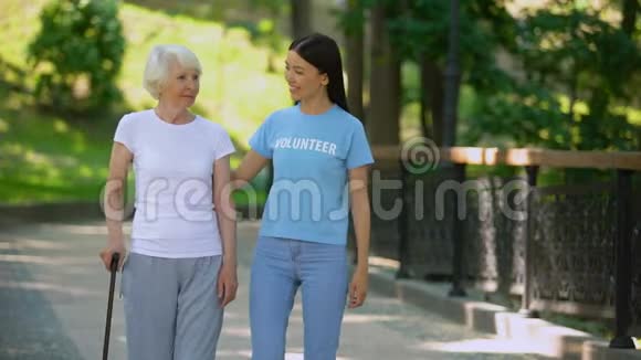 女性志愿者和老年病人有棍棒步行医院花园护理视频的预览图