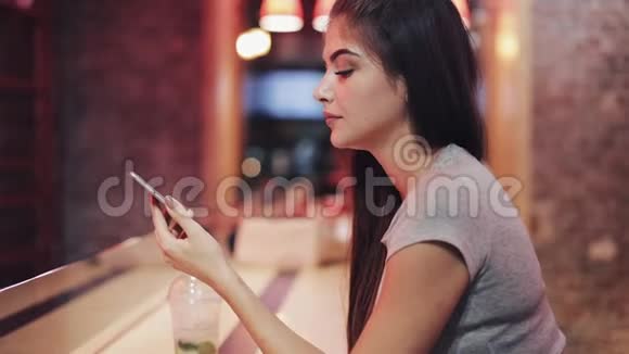 美女在夜酒吧用智能手机说话听语音留言享受夜生活的女人视频的预览图
