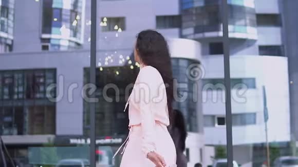 一个穿裙子的女孩在购物后手里拿着包裹对购买感到满意慢动作高清高清视频的预览图