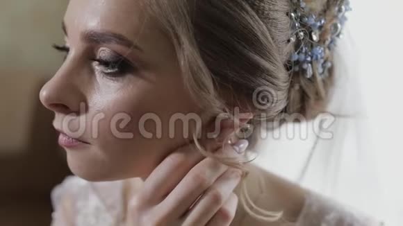 优雅的金发新娘戴着漂亮的耳环婚礼当天早上的女人视频的预览图