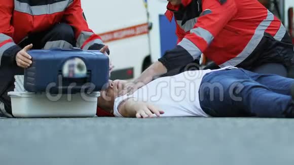 救护人员拯救躺在路上的男性病人医生设置滴管视频的预览图