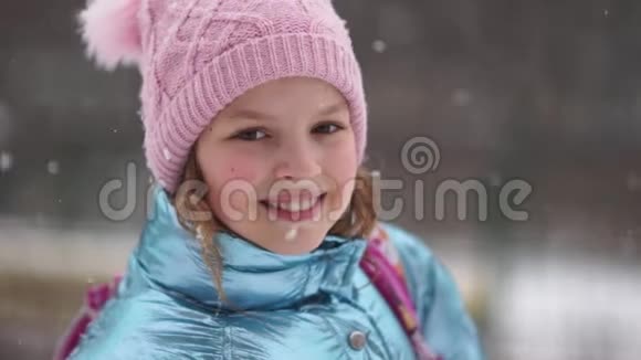 穿着粉红色针织帽子蓝色冬季夹克和背上背包的可爱女学生的肖像回到学校视频的预览图