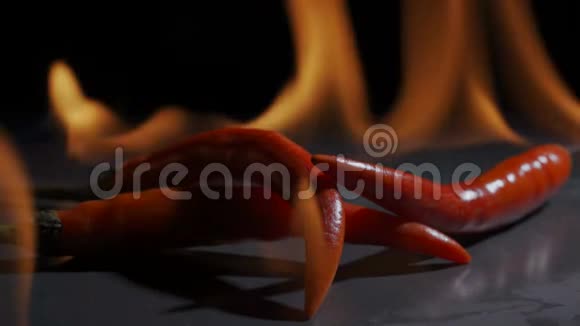 三个红辣椒躺在黑暗背景下的火焰中视频的预览图