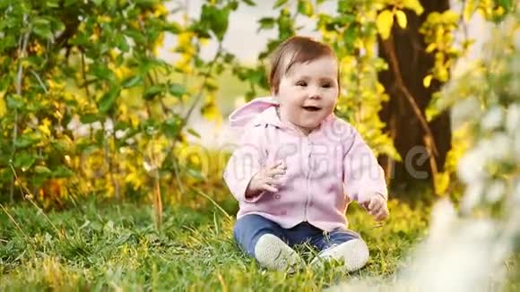 可爱的微笑宝宝在日落时坐在公园的绿草上视频的预览图