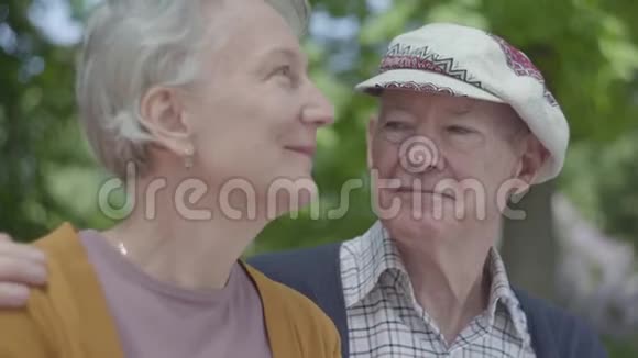 一对恋爱中的成熟夫妇坐在公园的长凳上的肖像成年妇女和老年丈夫投标关系视频的预览图