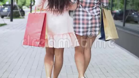 两个穿着漂亮衣服的女孩在购物中心附近购物后手里拿着一包东西买得很好视频的预览图