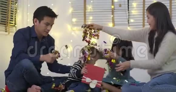 快乐的亚洲家庭坐在客厅的地板上玩纸屑视频的预览图