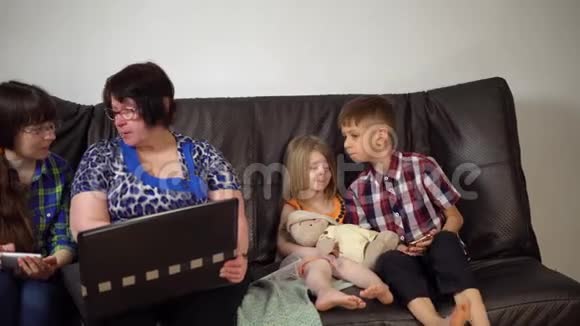 一家人坐在沙发上使用电子设备视频的预览图