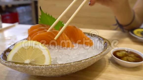 女人从盘子里拿出生鱼片日本菜式视频的预览图
