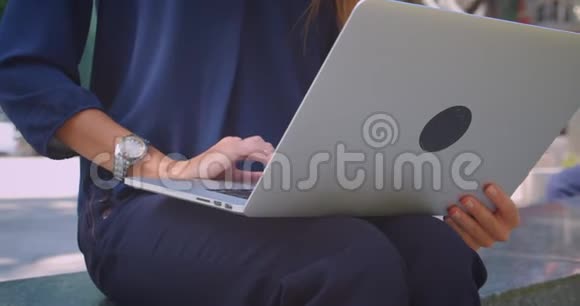 年轻迷人的高加索女商人在公园户外用笔记本电脑打字的特写照片视频的预览图