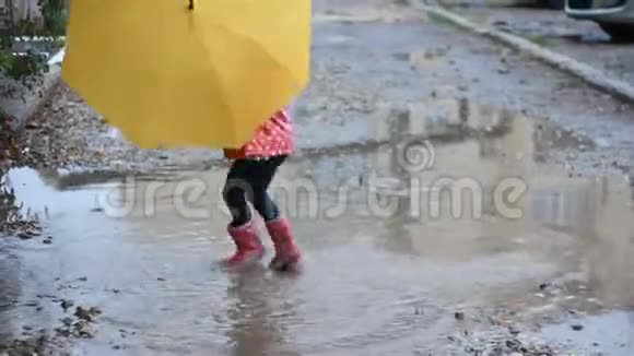 有趣的女孩在下雨天在水坑里跳和玩伞视频的预览图