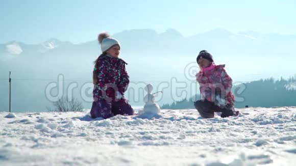 穿着户外服装的快乐的小女孩在阳光下站在户外撒雪视频的预览图