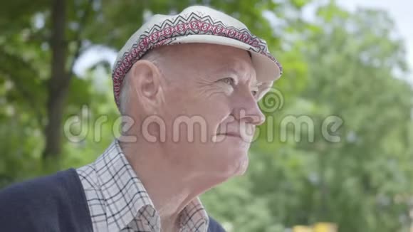 肖像老人坐在公园的长凳上可爱的成熟祖父在阳光明媚的春日户外休息视频的预览图