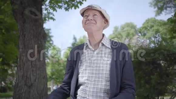 肖像可爱的老人坐在公园的长凳上可爱的成熟祖父在阳光明媚的春日里休息视频的预览图