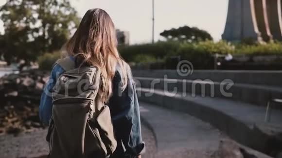镜头跟随美丽的白种人女游客背着背包漫步在布鲁克林公园混凝土河岸慢动作视频的预览图
