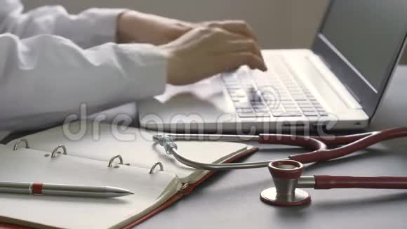关闭在工作场所工作的医生的笔记本电脑前景上的听诊器视频的预览图