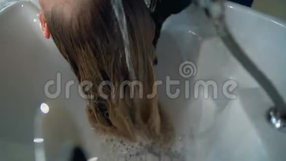女性在理发店洗头的时候接受头部按摩关闭理发师做头部按摩视频的预览图