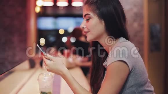 年轻迷人的女人美丽的微笑是使用智能手机在晚上和看镜头女孩视频的预览图