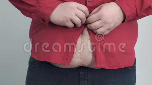 胖乎乎的男人试图把衬衫拉到他沉重的肚子上纽扣被撕掉了慢吞吞的视频的预览图