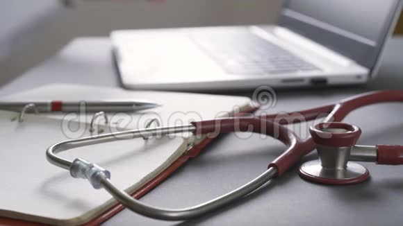 关闭在工作场所工作的医生的笔记本电脑前景上的听诊器视频的预览图