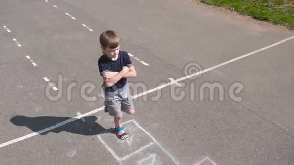 男孩在街上跳着玩跳房子前景视频的预览图