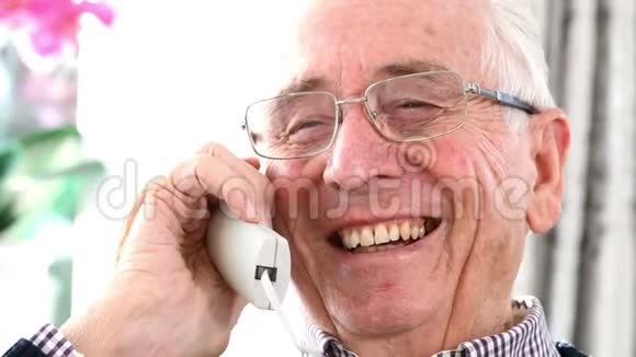 微笑老人在家讲电话视频的预览图