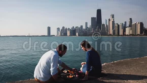 年轻的幸福夫妇在密歇根湖畔享受浪漫的约会可以看到美国芝加哥的全景视频的预览图