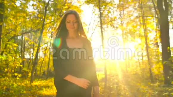 美丽的女孩穿着黑色的衣服在秋天的森林里散步享受着好天气慢动作视频的预览图