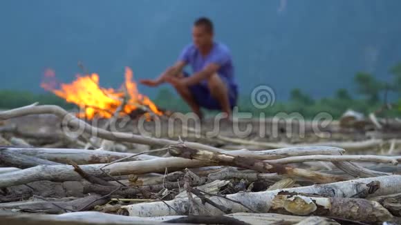 那个年轻人正在沙滩上的炉火旁取暖视频的预览图