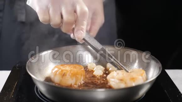 做海鲜健康的食物概念专业厨师在手套中烹饪葱用粗钳子把它们翻过来视频的预览图